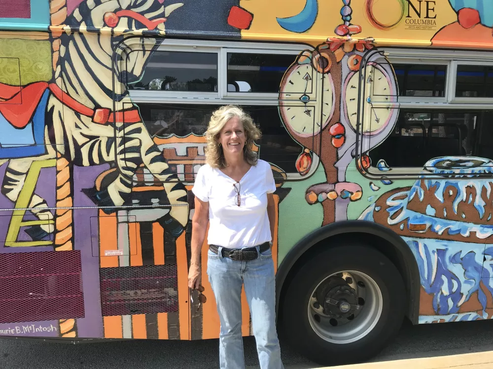 Photo of Laurie McIntosh in front of her work on the COMET Bus